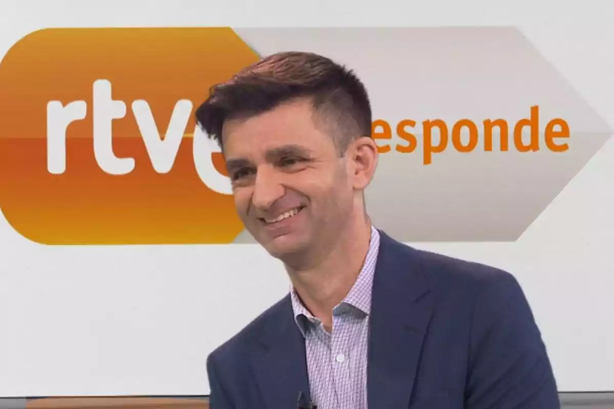 Un hombre sonriendo en un estudio de televisión con el logo de RTVE en el fondo.