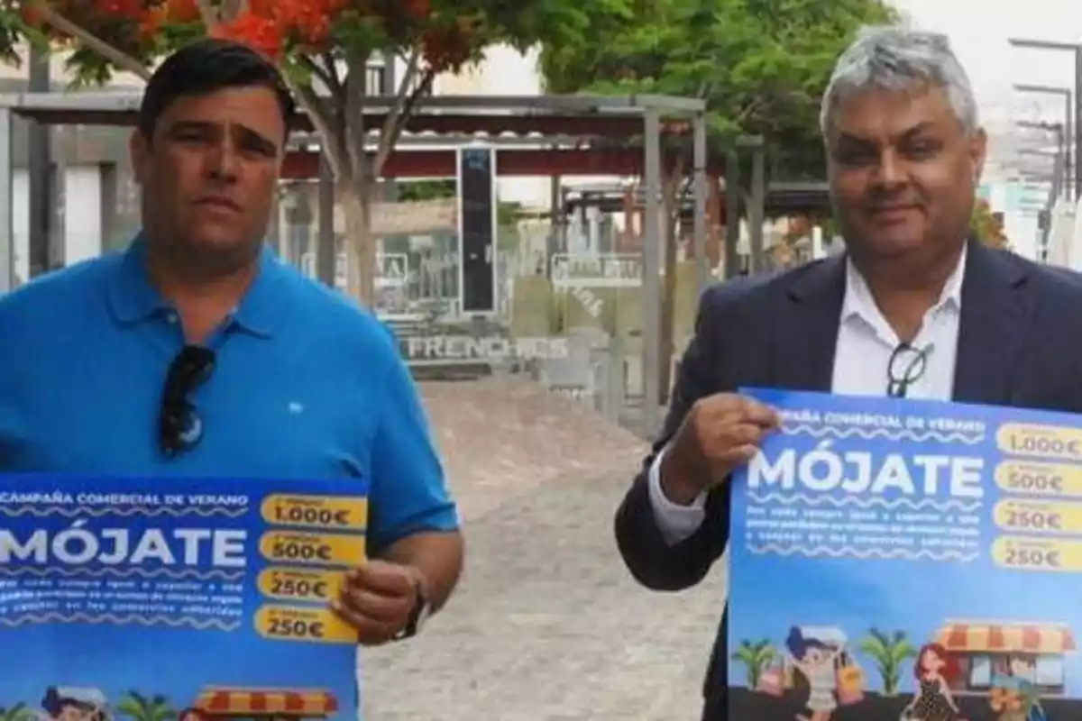 Dos hombres sosteniendo carteles promocionales de una campaña comercial de verano llamada 