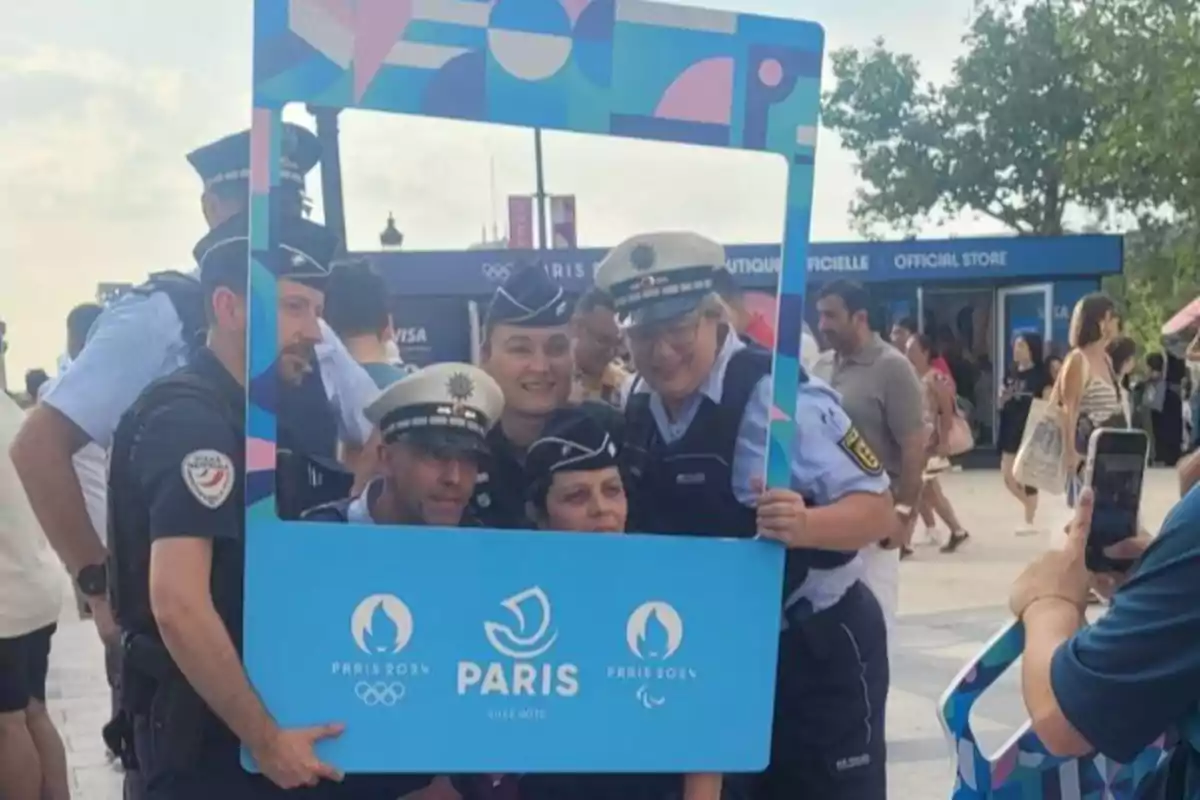 Un grupo de policías posando con un marco promocional de los Juegos Olímpicos y Paralímpicos de París 2024.