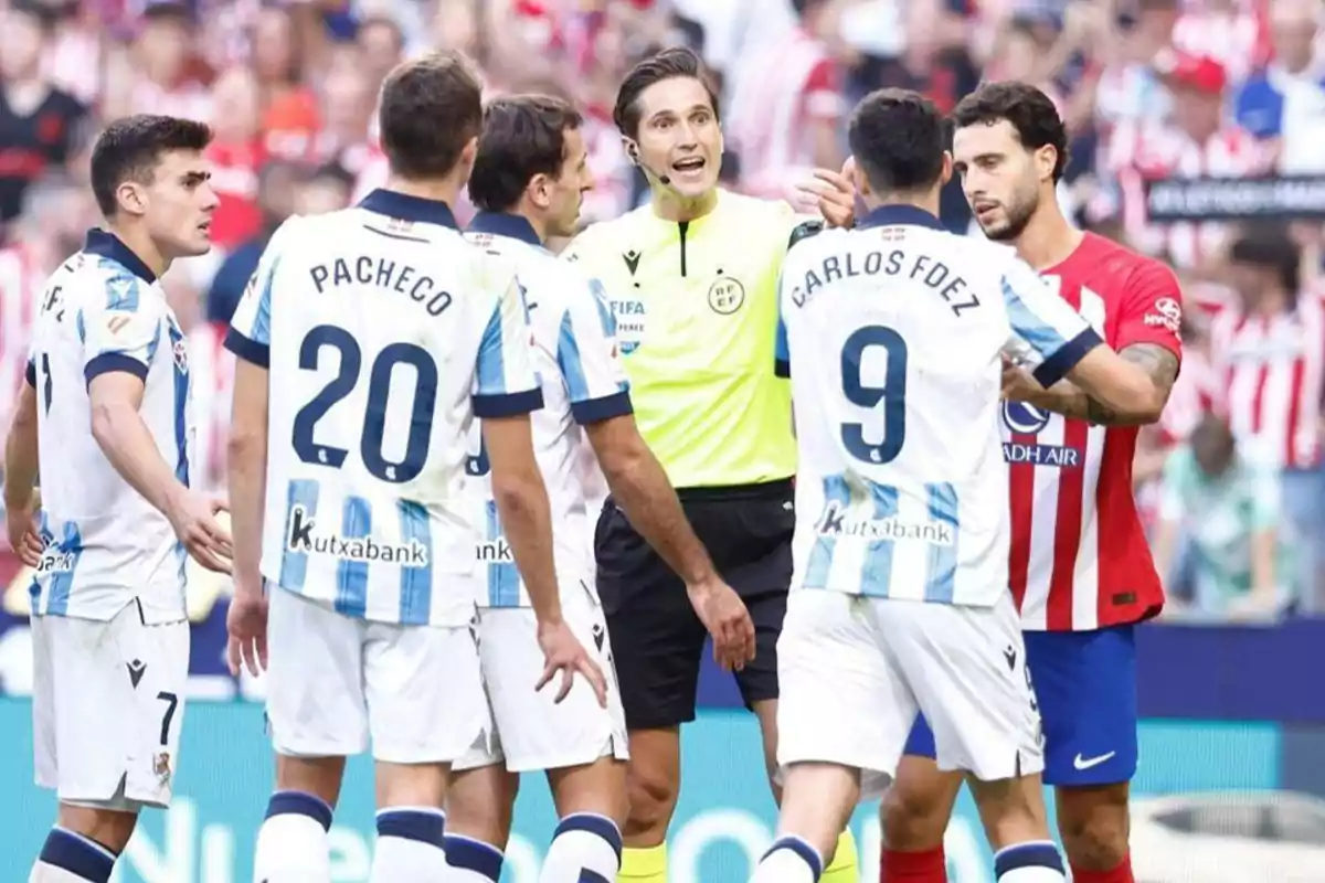 Jugadores de fútbol discuten con el árbitro durante un partido.