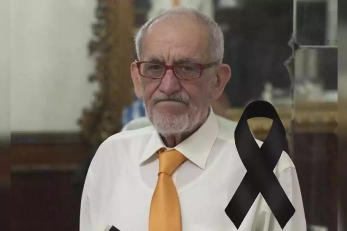 Un hombre mayor con gafas y corbata naranja, junto a un lazo negro de luto.