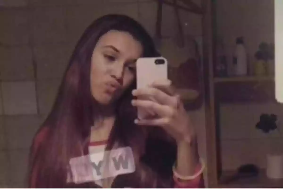 Joven tomándose una selfie frente a un espejo en un baño Joven tomándose una selfie frente a un espejo en un baño