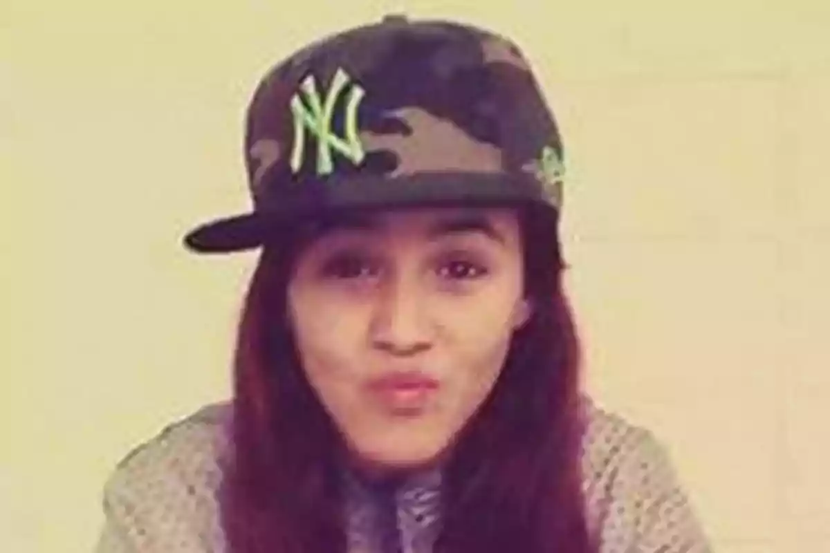 Joven con gorra de camuflaje y logotipo verde haciendo un gesto divertido frente a la cámara Joven con gorra de camuflaje y logotipo verde haciendo un gesto divertido frente a la cámara