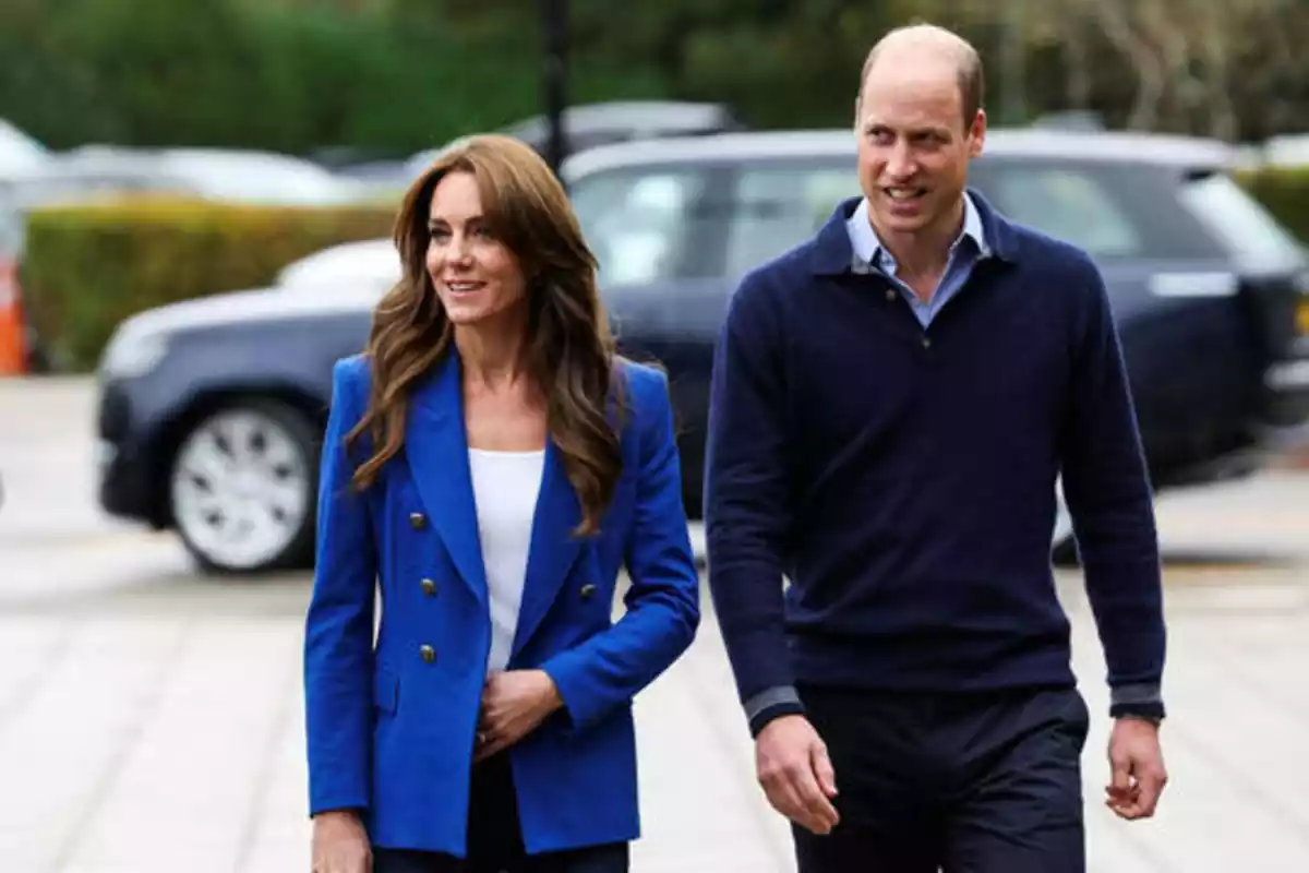 Kate Middleton y el príncipe Guillermo, futuros soberanos del trono británico. Caminan uno al lado del otro, pero separados. Guillermo viste de azul marino y Kate con una blazer azul eléctrico.
