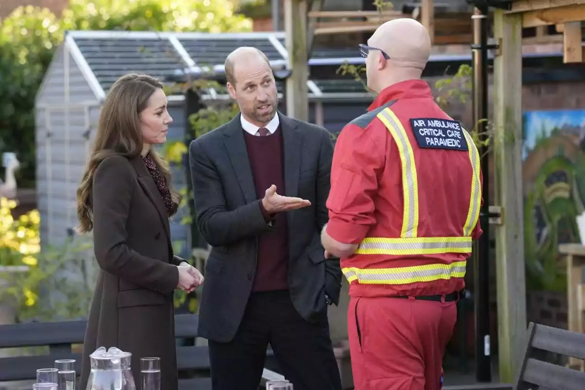 Kate Middleton y el príncipe Guillermo conversan con un paramédico de cuidados críticos de ambulancia aérea en un entorno al aire libre. Kate Middleton y el príncipe Guillermo conversan con un paramédico de cuidados críticos de ambulancia aérea en un entorno al aire libre.