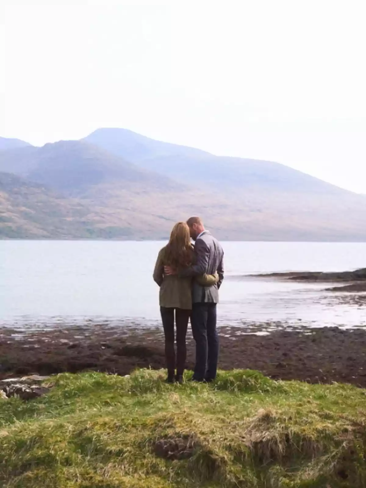 Una pareja abrazada de espaldas mirando un lago con montañas al fondo. Una pareja abrazada de espaldas mirando un lago con montañas al fondo.