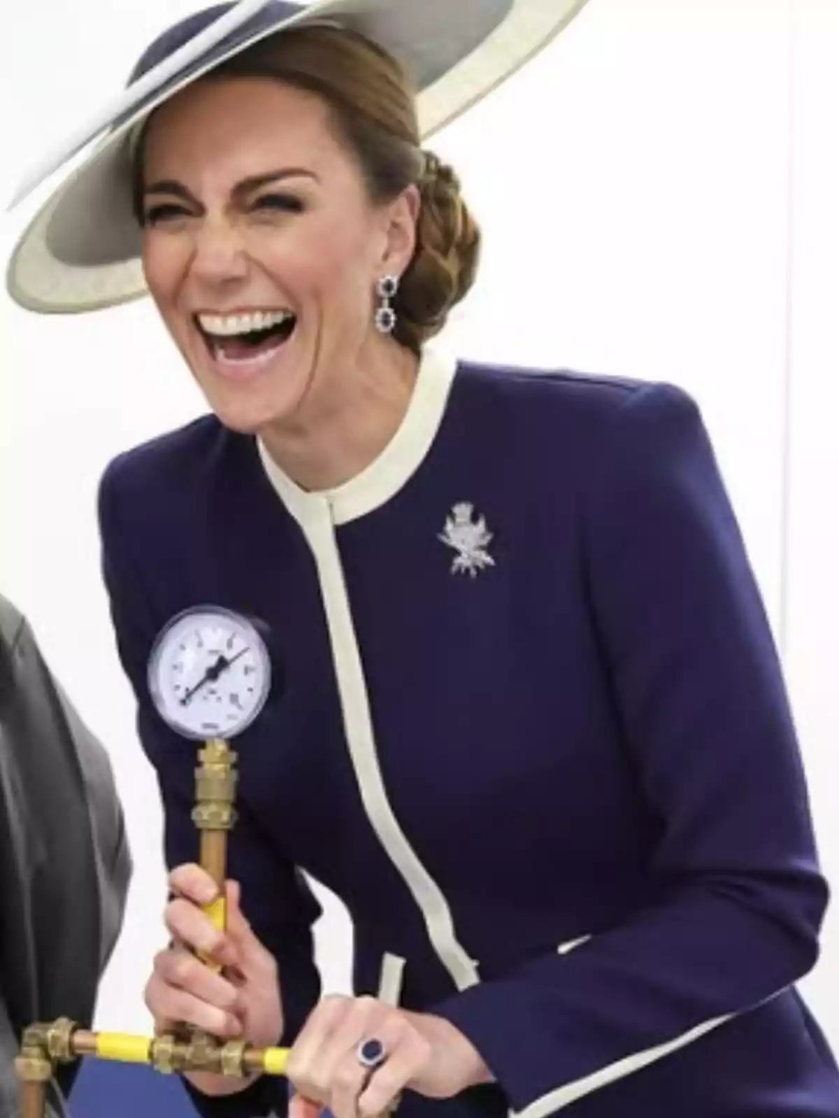 Una mujer sonriente con un sombrero elegante y un traje azul oscuro sostiene un medidor de presión. Una mujer sonriente con un sombrero elegante y un traje azul oscuro sostiene un medidor de presión.