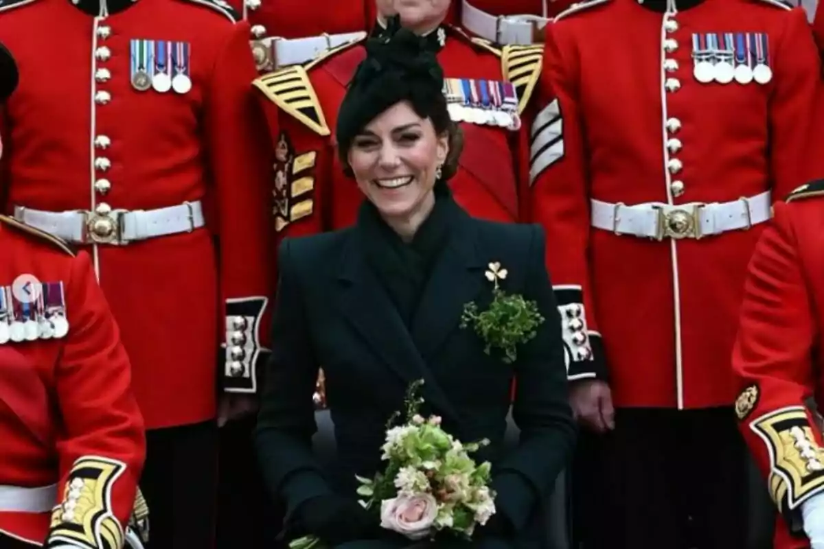 Una mujer sonriente vestida de negro con un ramo de flores en las manos, rodeada de personas con uniformes rojos decorados con medallas. Una mujer sonriente vestida de negro con un ramo de flores en las manos, rodeada de personas con uniformes rojos decorados con medallas.