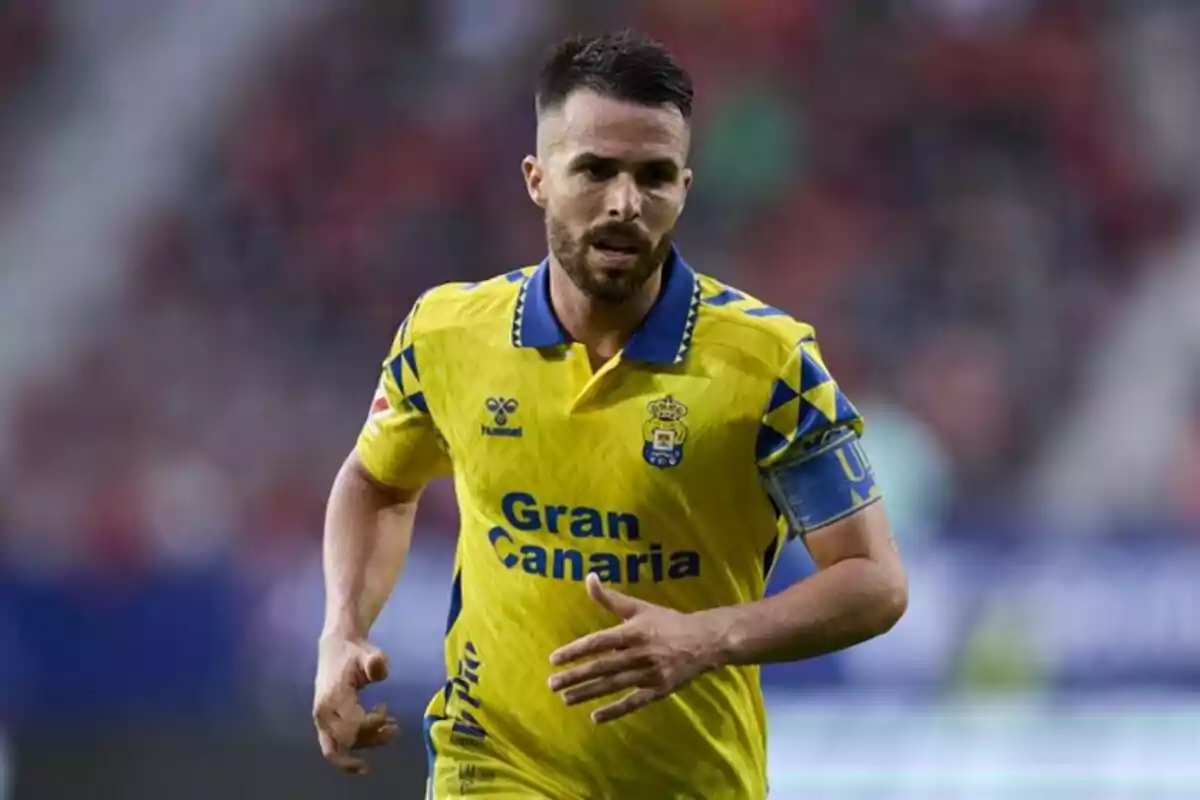 Un jugador de fútbol con uniforme amarillo y azul corre en el campo durante un partido.