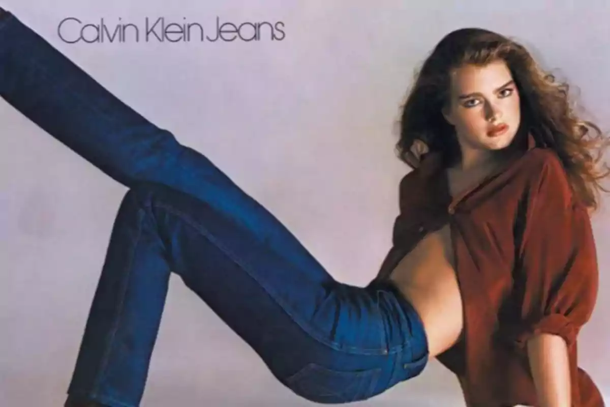 Una mujer posando con jeans y una camisa marrón en un anuncio de Calvin Klein Jeans.