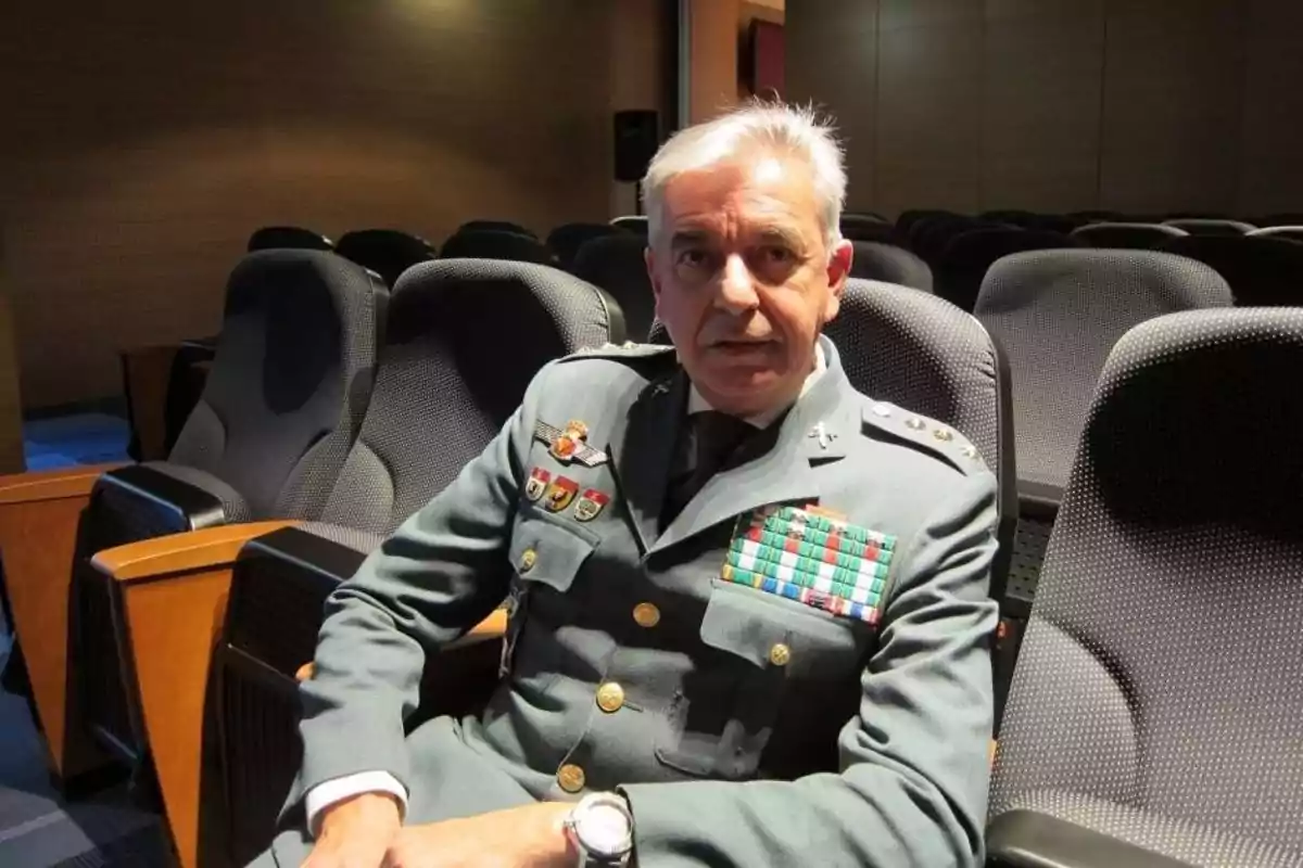 Hombre de cabello canoso con uniforme militar sentado en una sala de butacas vacía Hombre de cabello canoso con uniforme militar sentado en una sala de butacas vacía