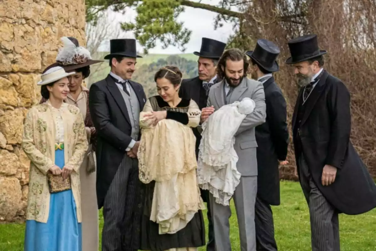 Un grupo de personas vestidas con ropa de época posan al aire libre mientras dos de ellas sostienen bebés envueltos en mantas elegantes. Captura de 'La Promesa' Un grupo de personas vestidas con ropa de época posan al aire libre mientras dos de ellas sostienen bebés envueltos en mantas elegantes. Captura de 'La Promesa'