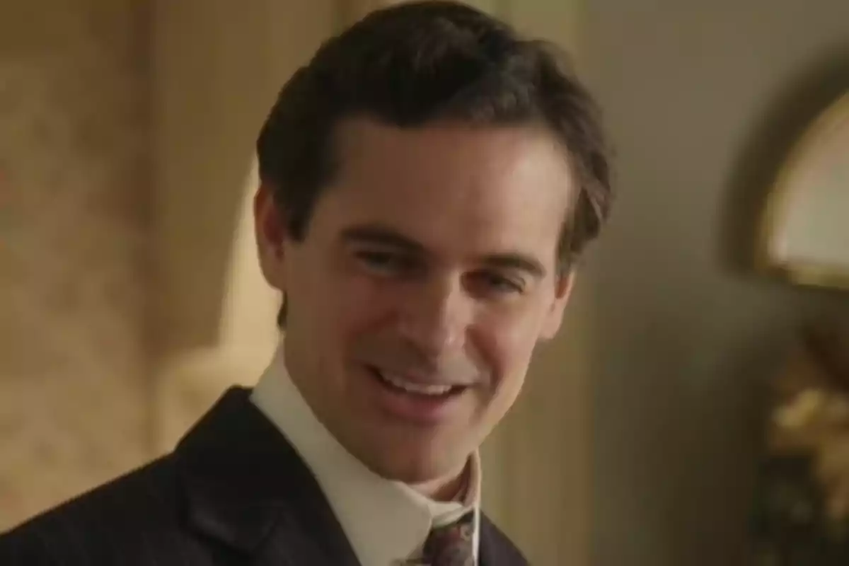 Jacobo con traje elegante sonriendo en un ambiente interior iluminado. Captura de 'La promesa' Jacobo con traje elegante sonriendo en un ambiente interior iluminado. Captura de 'La promesa'