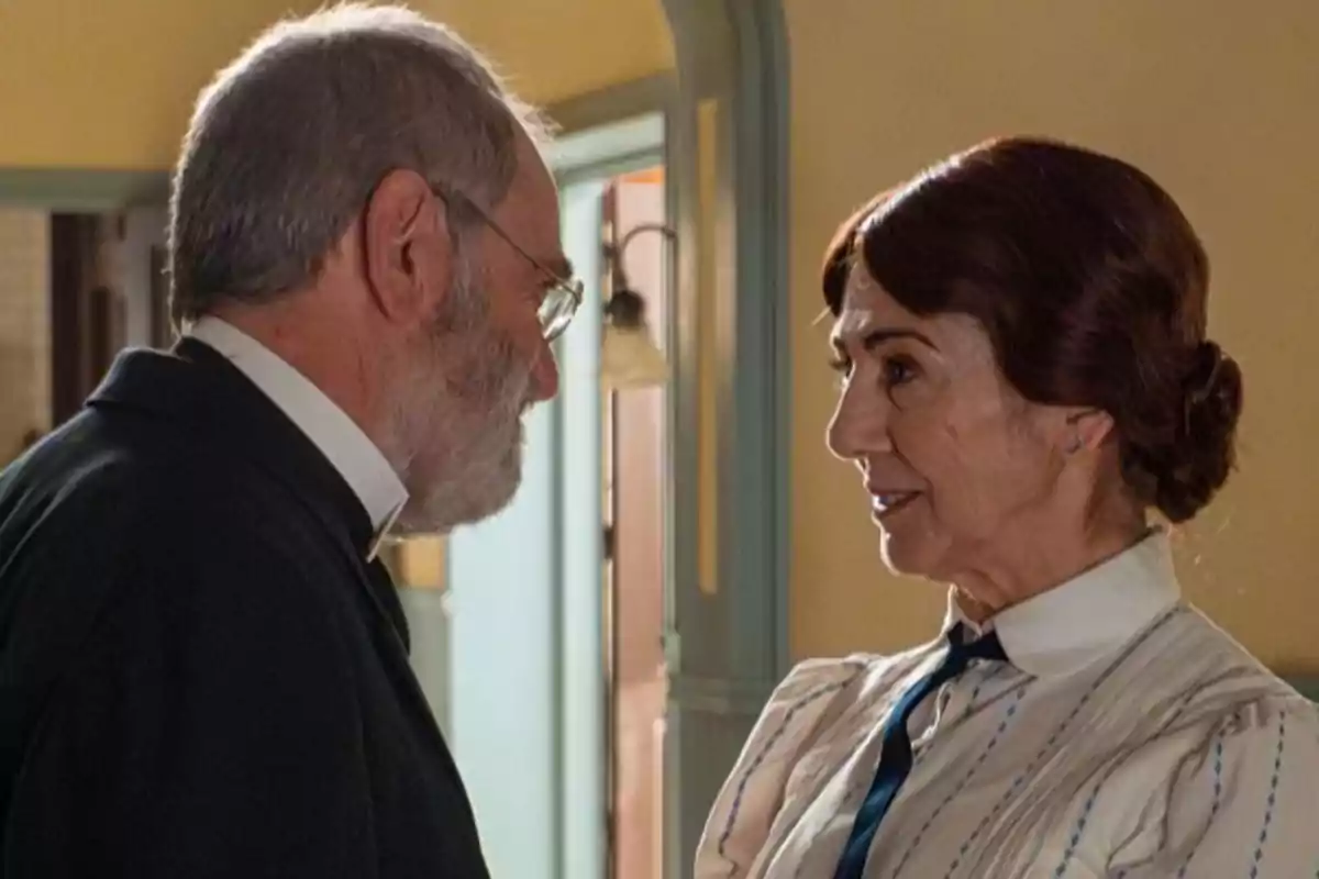 Rómulo conversa de cerca con Emilia de cabello recogido y blusa clara en una habitación iluminada. Captura de 'La Promesa' Rómulo conversa de cerca con Emilia de cabello recogido y blusa clara en una habitación iluminada. Captura de 'La Promesa'