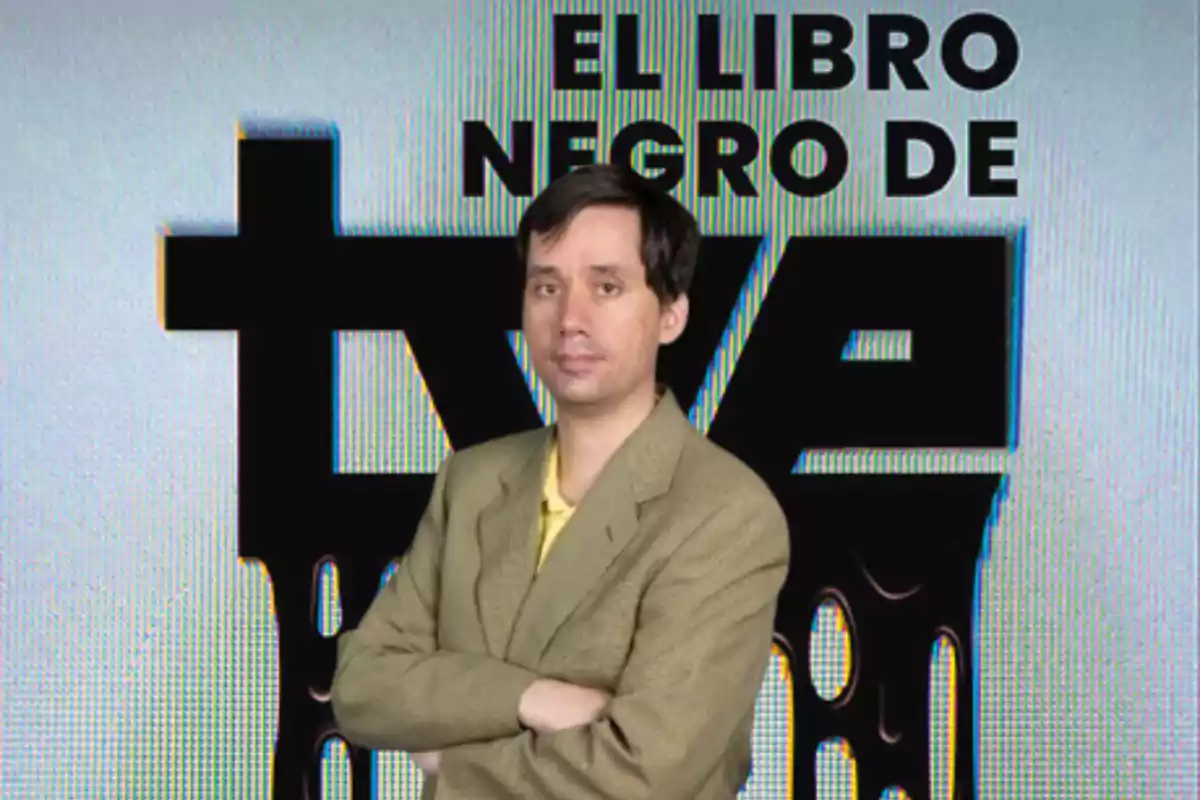 Un hombre con traje claro y camisa amarilla está de pie con los brazos cruzados frente a un fondo que dice "El libro negro de TVE".