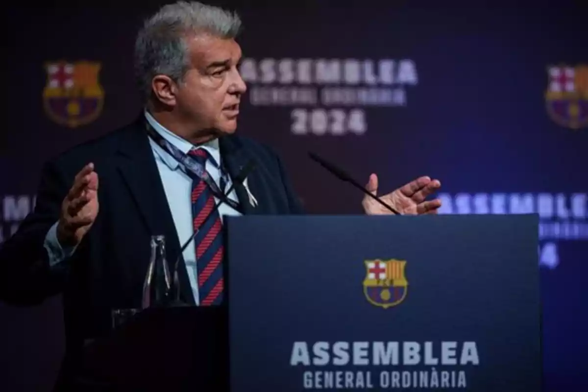 Un hombre en un podio hablando en una asamblea general ordinaria del FC Barcelona.