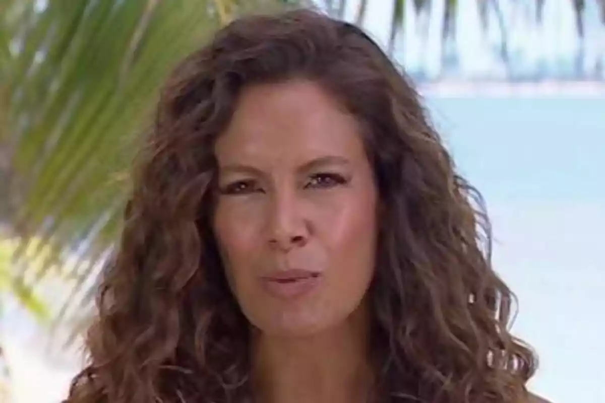 Laura Madrueño con cabello rizado y expresión seria en un entorno tropical con palmeras y el mar de fondo en Supervivientes. Laura Madrueño con cabello rizado y expresión seria en un entorno tropical con palmeras y el mar de fondo en Supervivientes.