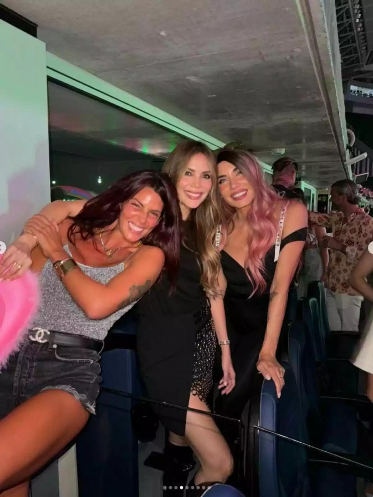 Laura Matamoros, Rosanna Zanetti y Pilar Rubio posan juntas y sonríen en un evento nocturno, Pilar lleva una peluca rosa, Rosanna un vestido negro y Laura un top gris con shorts de mezclilla. Post de Laura en Instagram el 21 de julio de 2024