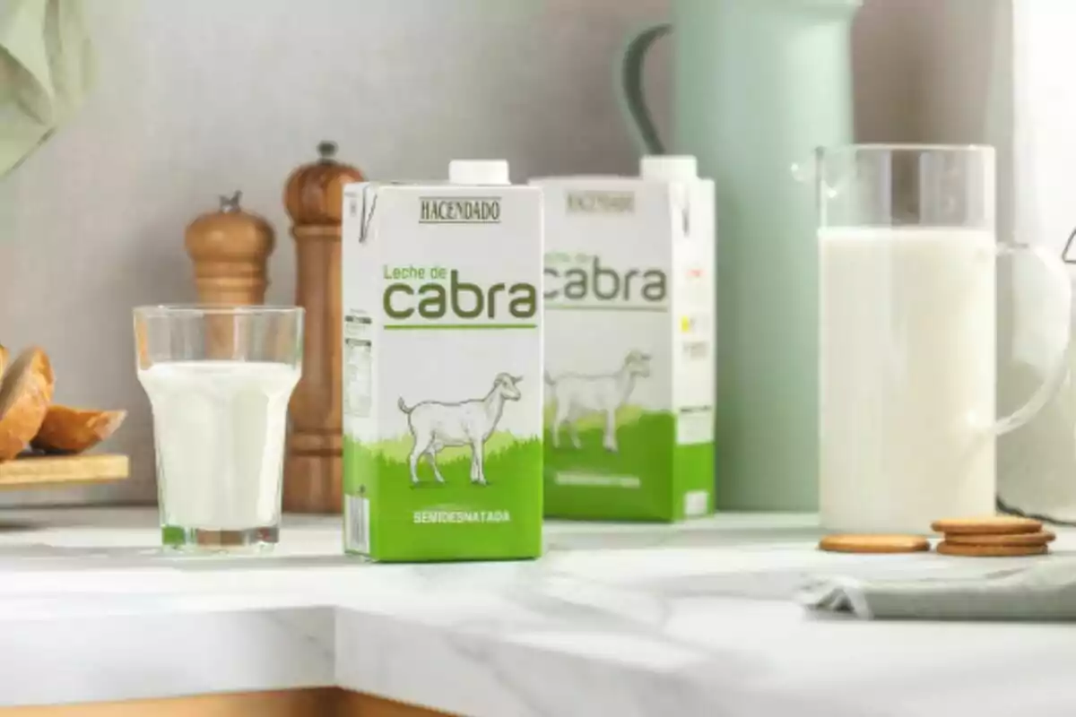 Caja de leche de cabra semidesnatada de la marca Hacendado sobre una mesa junto a un vaso de leche, una jarra y algunas galletas. Caja de leche de cabra semidesnatada de la marca Hacendado sobre una mesa junto a un vaso de leche, una jarra y algunas galletas.