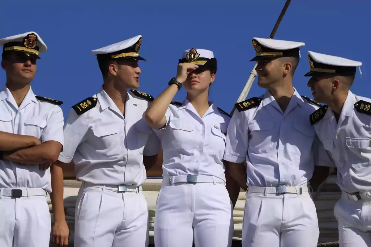 Un grupo de cadetes navales en uniforme blanco posando juntos bajo un cielo azul. Un grupo de cadetes navales en uniforme blanco posando juntos bajo un cielo azul.