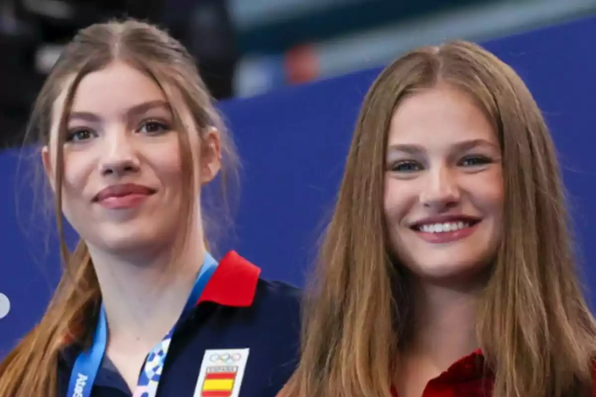 Dos jóvenes sonrientes, una de ellas lleva una medalla y un uniforme con el escudo de España.