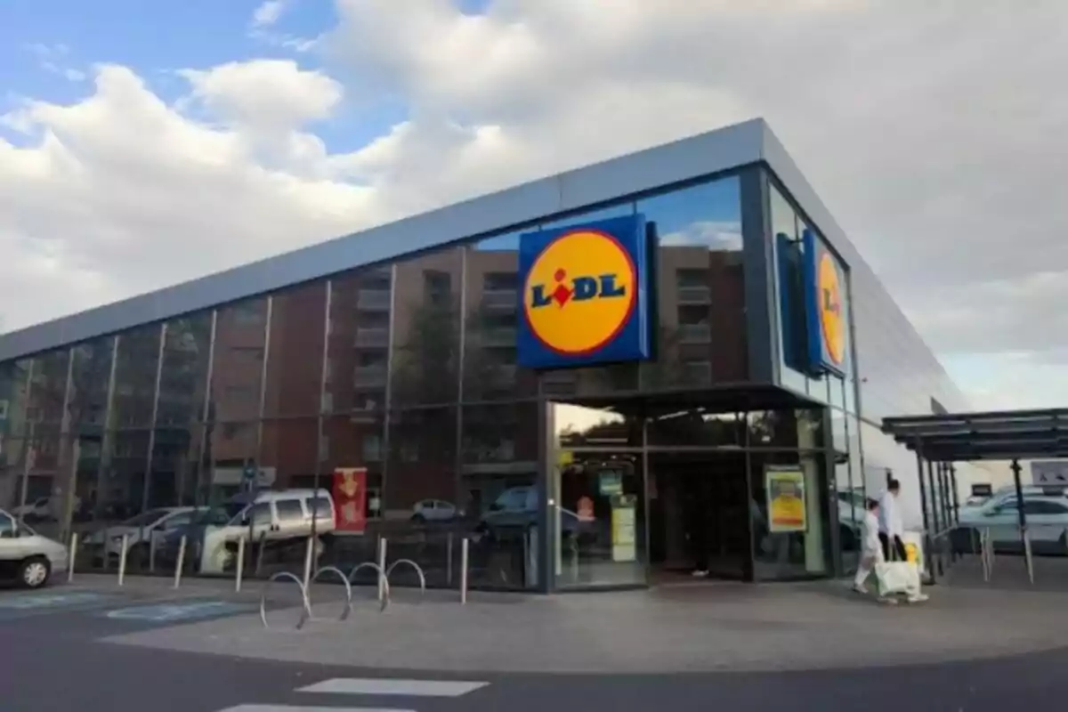 Fachada de un supermercado con un gran letrero en la entrada y un cielo parcialmente nublado. Fachada de un supermercado con un gran letrero en la entrada y un cielo parcialmente nublado.