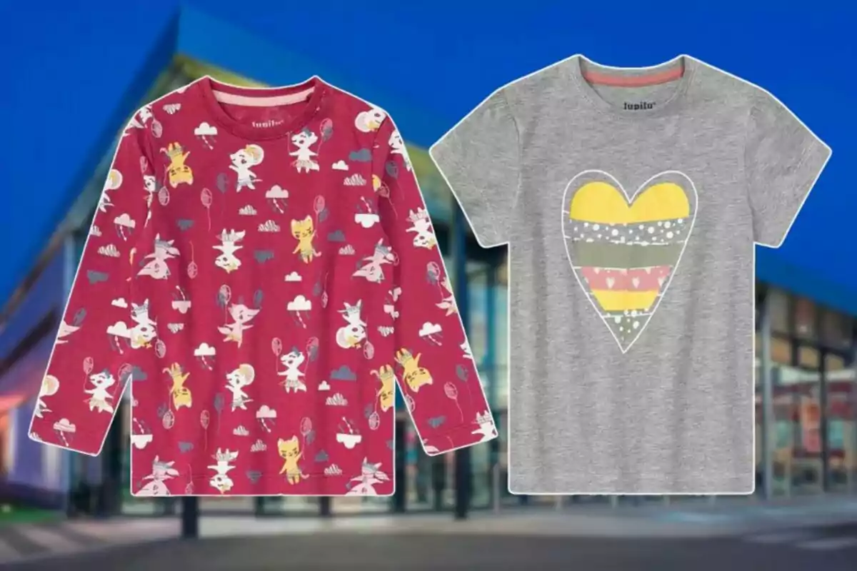 Dos camisetas infantiles, una roja con estampado de personajes y otra gris con un corazón de colores, sobre un fondo de edificio moderno. Dos camisetas infantiles, una roja con estampado de personajes y otra gris con un corazón de colores, sobre un fondo de edificio moderno.