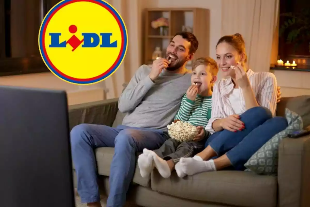 Una familia sentada en un sofá comiendo palomitas mientras mira la televisión con el logo de Lidl en la esquina superior izquierda.