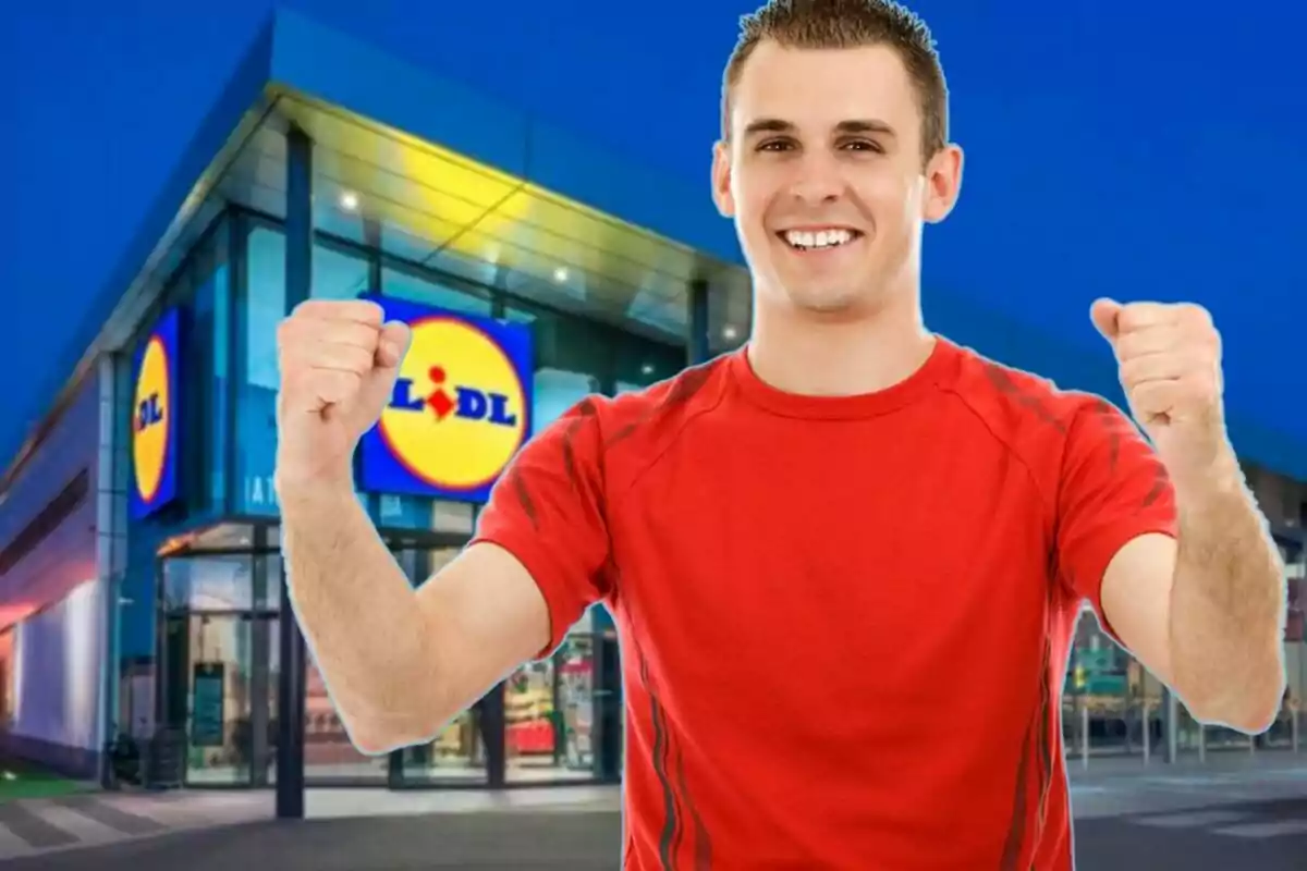 Un hombre sonriente con camiseta roja levanta los puños frente a una tienda Lidl.