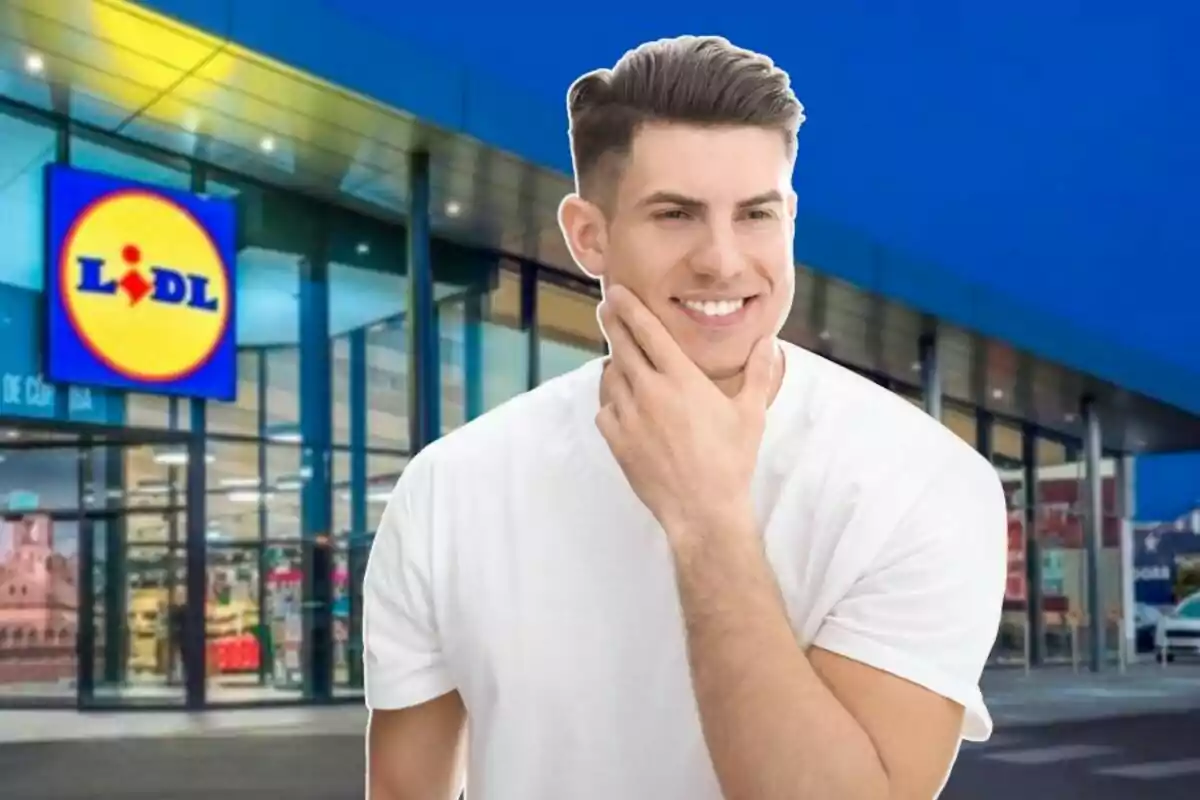 Un hombre sonriente con camiseta blanca frente a una tienda Lidl.