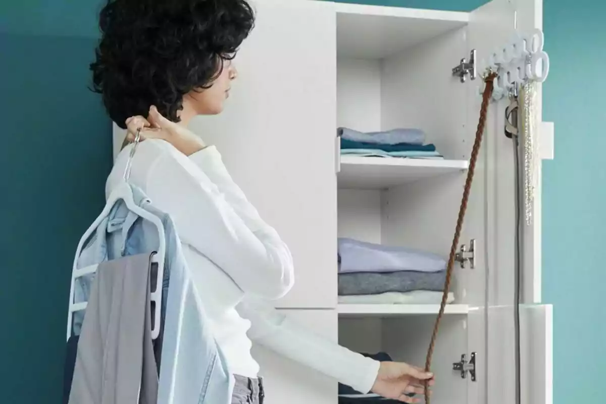 Persona de cabello rizado organizando ropa y accesorios en un armario blanco con estantes y ganchos para colgar prendas y cinturones Persona de cabello rizado organizando ropa y accesorios en un armario blanco con estantes y ganchos para colgar prendas y cinturones