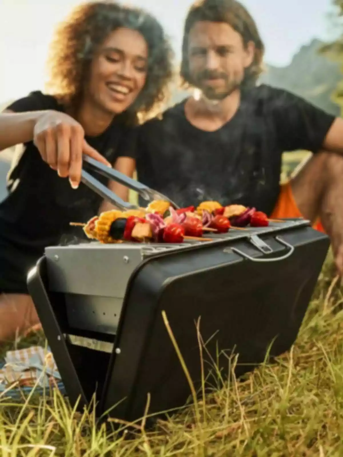 Una pareja disfruta de una parrillada al aire libre en un día soleado, cocinando verduras en una parrilla portátil sobre el césped. Una pareja disfruta de una parrillada al aire libre en un día soleado, cocinando verduras en una parrilla portátil sobre el césped.