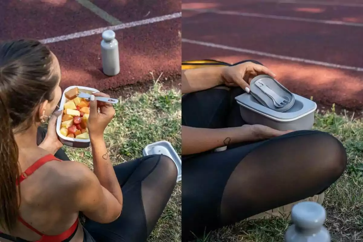 Una persona sentada en el césped junto a una pista deportiva disfrutando de una ensalada de frutas en un recipiente mientras sostiene una botella de agua y luego cierra el recipiente con una tapa que incluye cubiertos. Una persona sentada en el césped junto a una pista deportiva disfrutando de una ensalada de frutas en un recipiente mientras sostiene una botella de agua y luego cierra el recipiente con una tapa que incluye cubiertos.