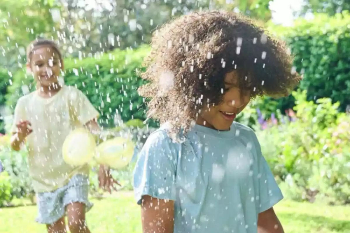 Dos niños jugando con globos de agua en un jardín bajo el sol. Dos niños jugando con globos de agua en un jardín bajo el sol.