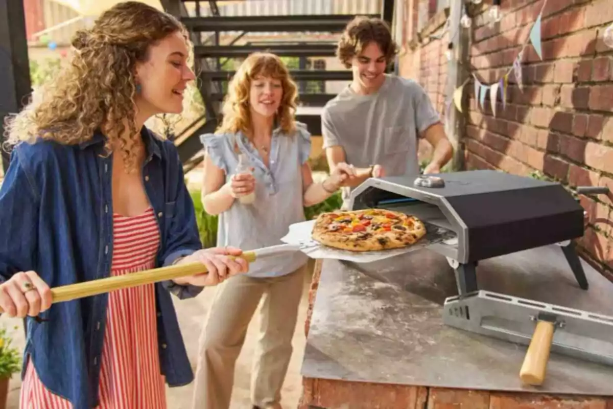 Personas disfrutando de una pizza recién horneada en un horno al aire libre. Personas disfrutando de una pizza recién horneada en un horno al aire libre.