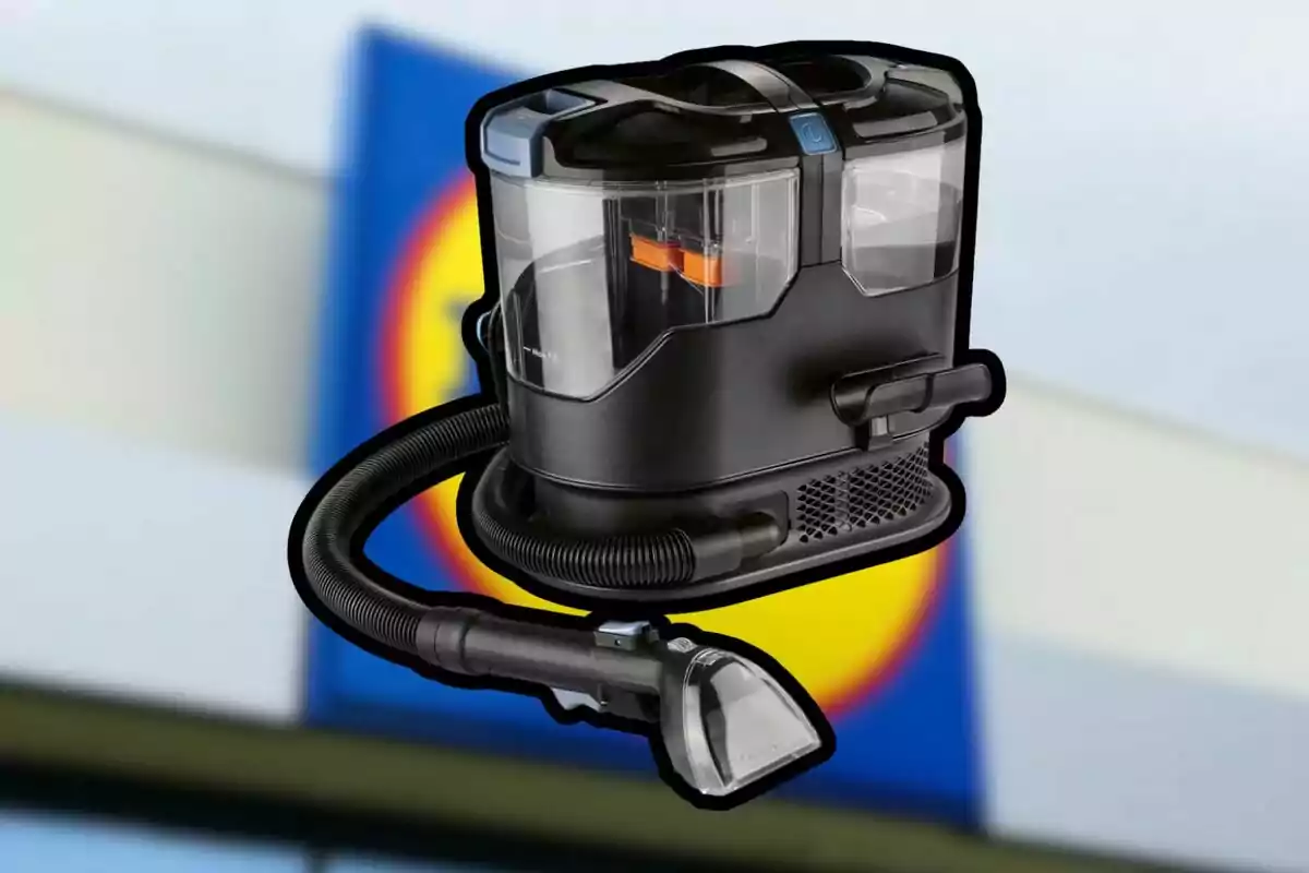 Una aspiradora negra con depósito transparente y manguera flexible frente a un fondo desenfocado con colores azul y amarillo. Una aspiradora negra con depósito transparente y manguera flexible frente a un fondo desenfocado con colores azul y amarillo.