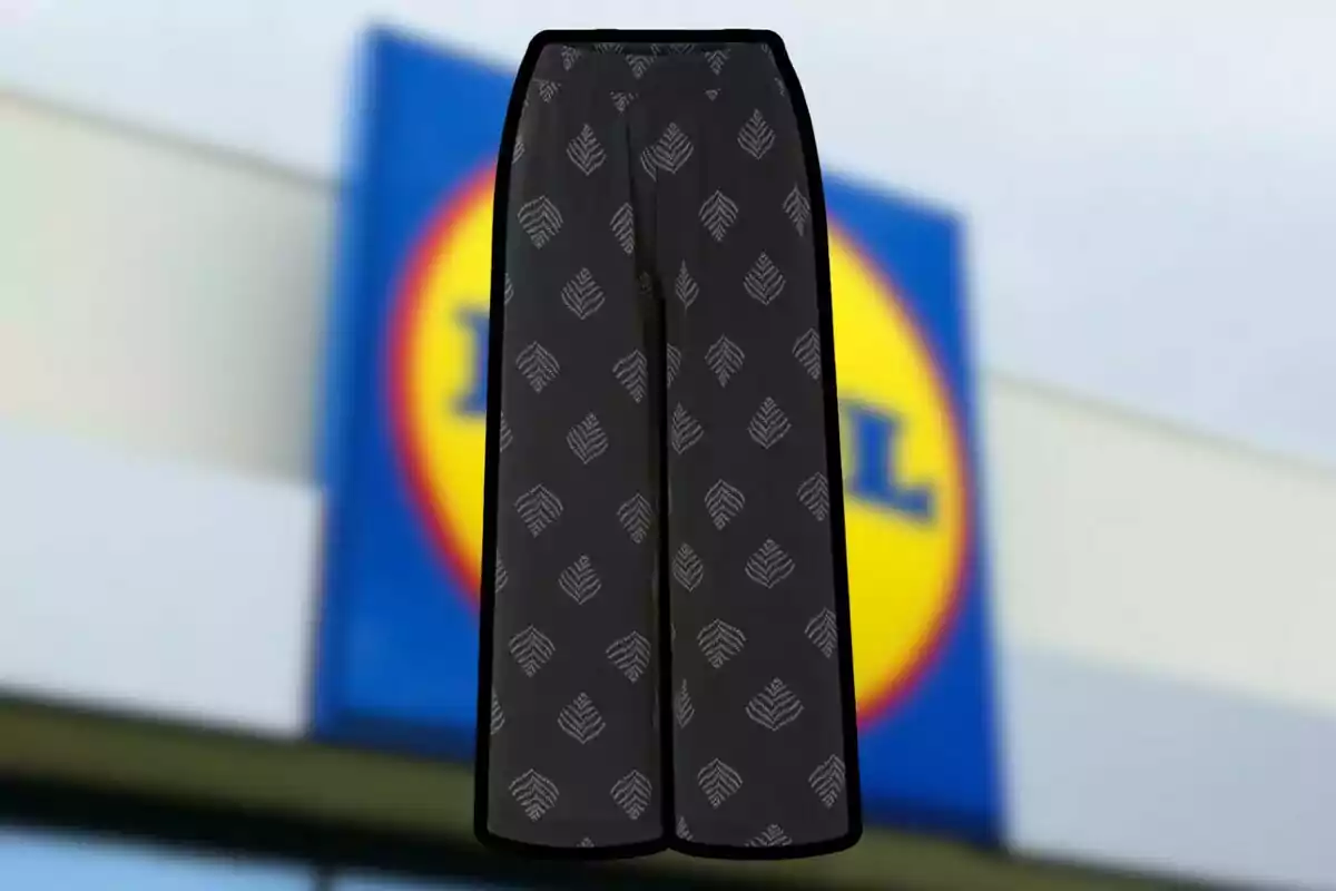 Pantalón negro con estampado de hojas blancas al frente de un letrero borroso de una tienda. Pantalón negro con estampado de hojas blancas al frente de un letrero borroso de una tienda.