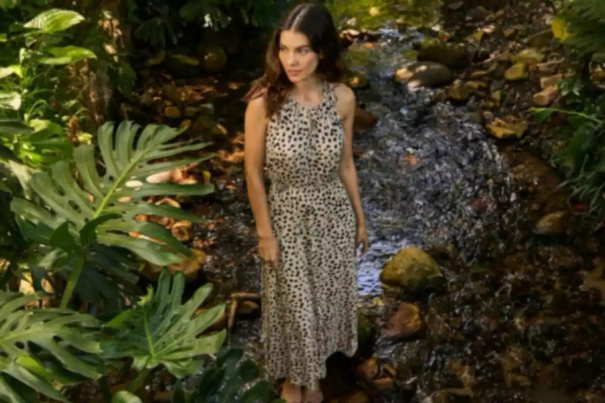 Mujer con vestido de estampado animal en un entorno natural con vegetación y un arroyo. Mujer con vestido de estampado animal en un entorno natural con vegetación y un arroyo.