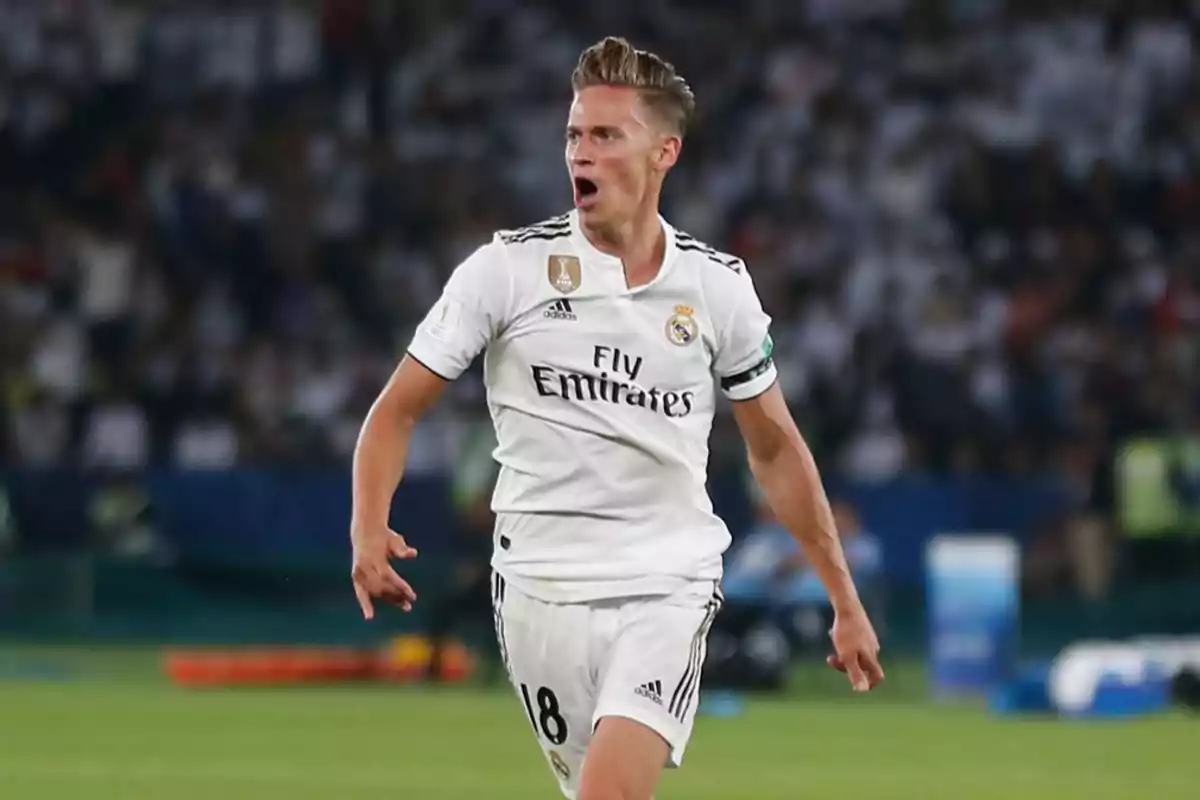 Un jugador de fútbol con uniforme blanco del Real Madrid celebra en el campo durante un partido. Un jugador de fútbol con uniforme blanco del Real Madrid celebra en el campo durante un partido.