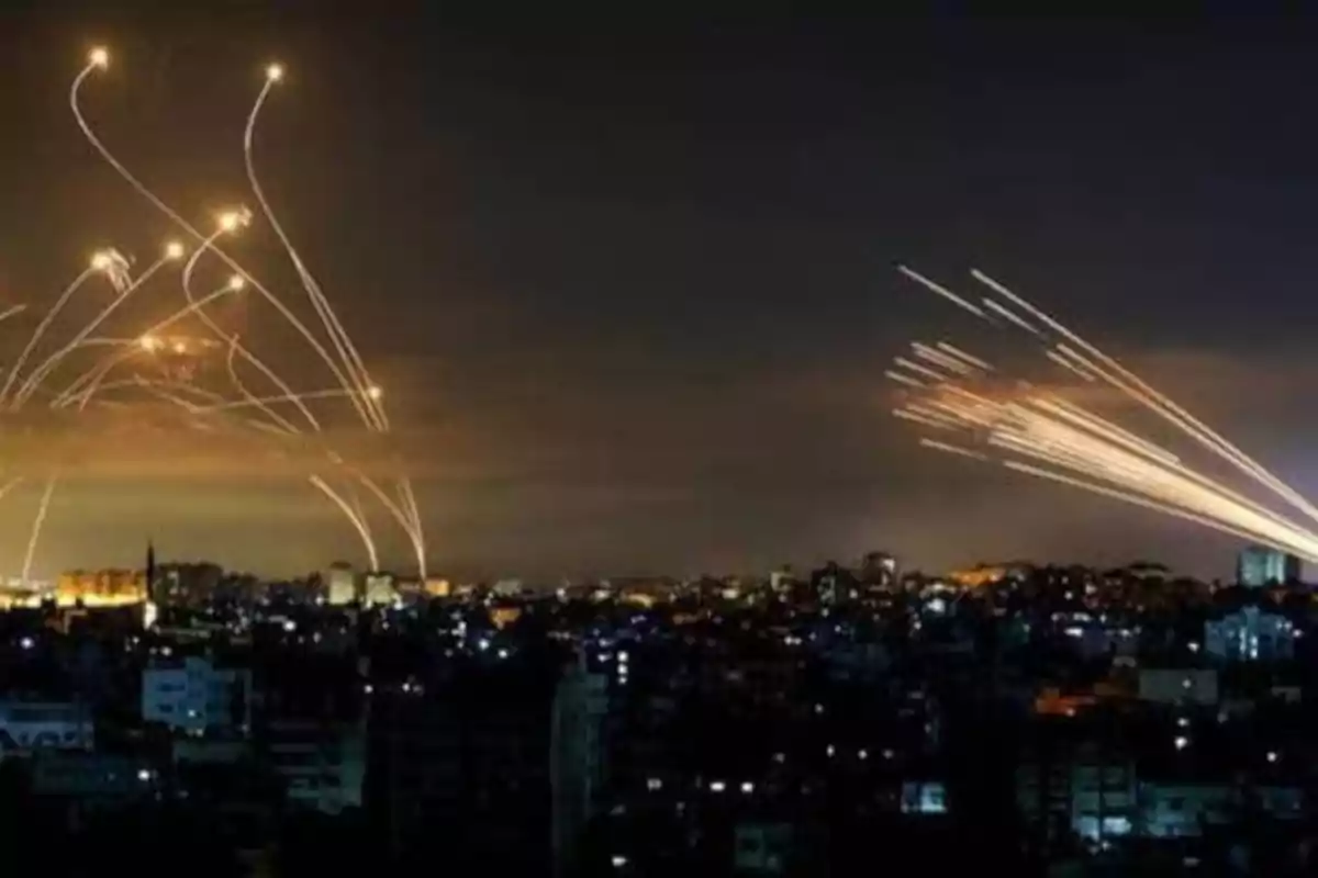 Cielos nocturnos sobre una ciudad con trazos de luces en el aire, posiblemente de cohetes o misiles.