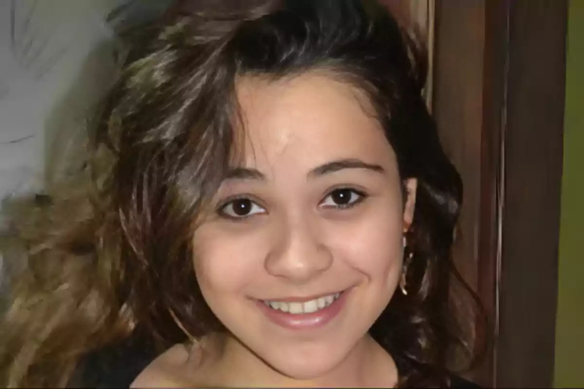 Una joven sonriente con cabello castaño y rizado.