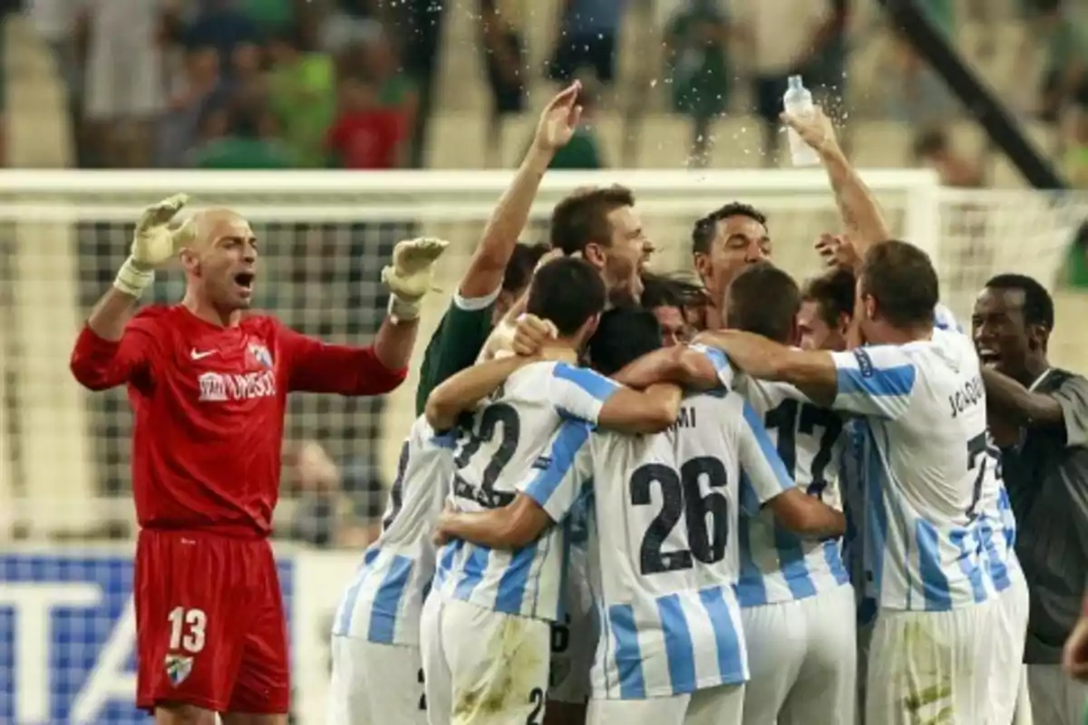 Jugadores de fútbol celebran en grupo en el campo de juego.