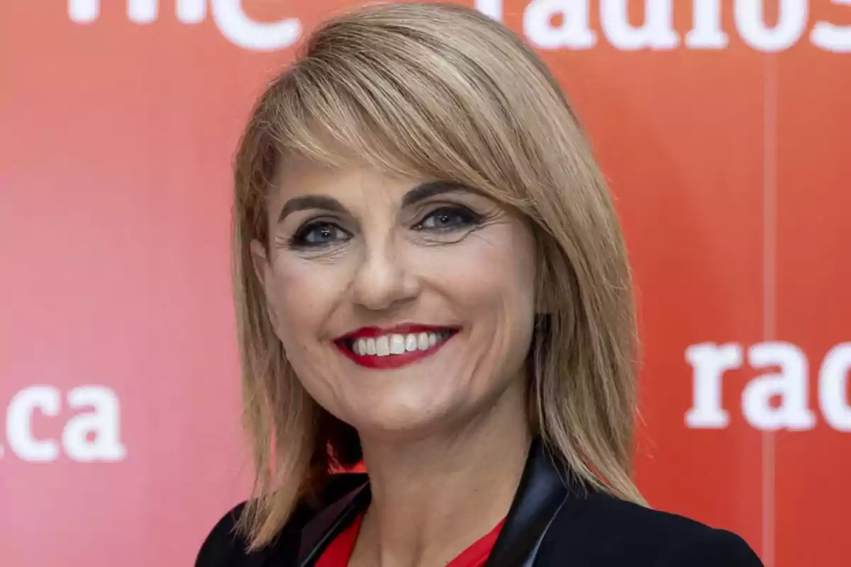 Una persona sonriendo frente a un fondo rojo con texto blanco. Una persona sonriendo frente a un fondo rojo con texto blanco.