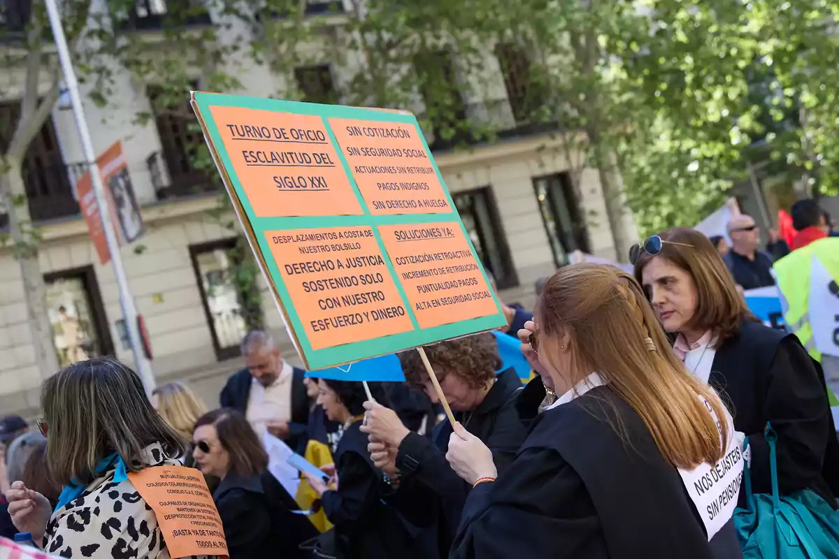 Personas en una manifestación sostienen carteles con mensajes sobre condiciones laborales y demandas de justicia social.