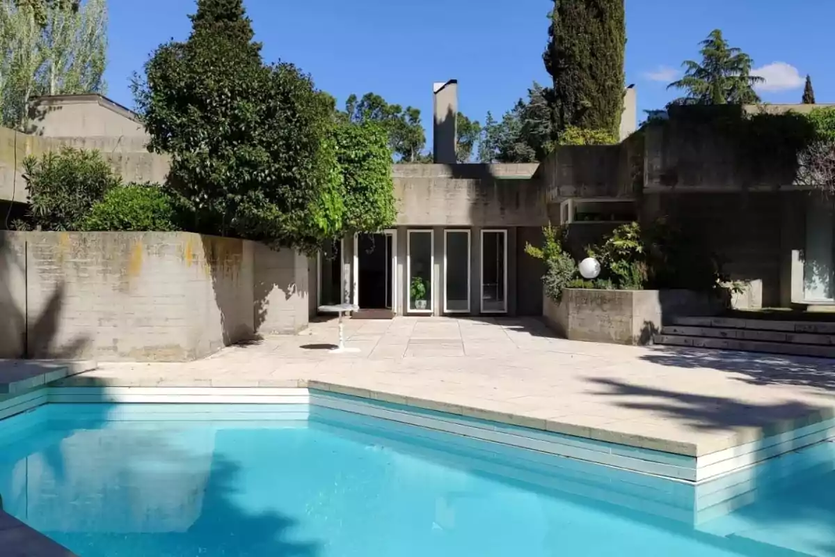Casa moderna con piscina y jardín rodeada de árboles y vegetación.