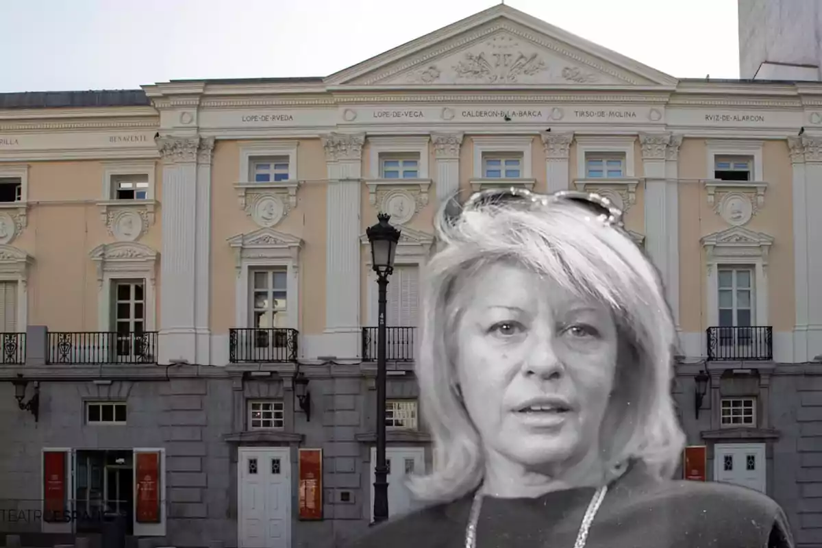 Una mujer en primer plano en blanco y negro frente a un edificio clásico con columnas y detalles arquitectónicos ornamentados.