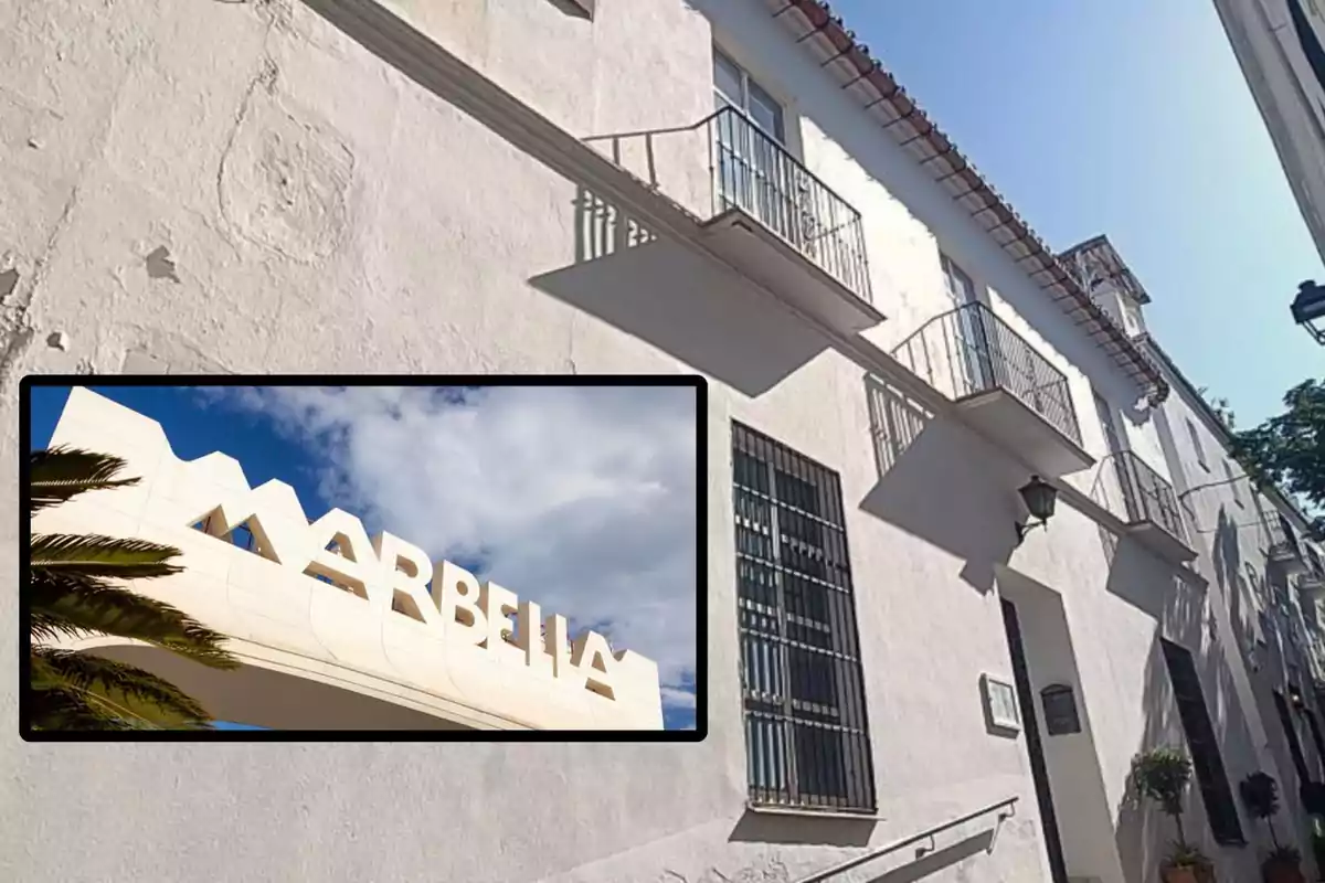 Edificio blanco con balcones en una calle de Marbella, con un cartel que dice "Marbella" en la esquina inferior izquierda.