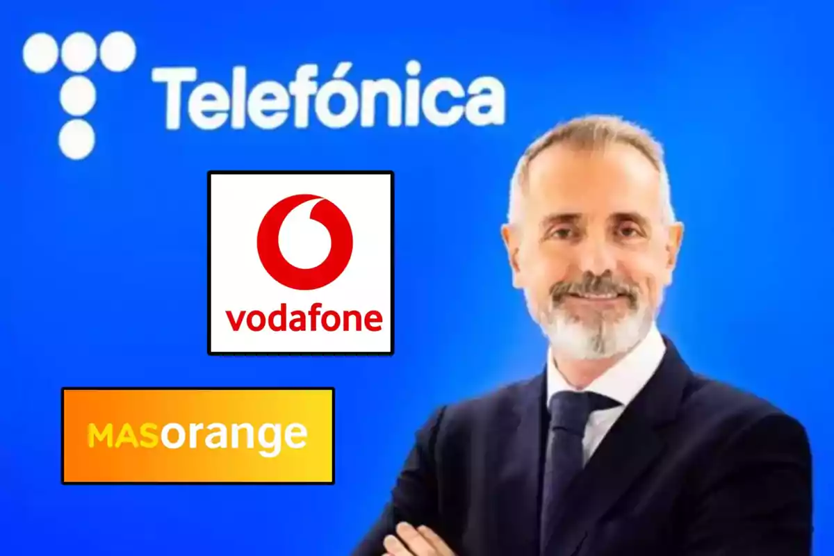 Un hombre de traje sonríe frente a un fondo azul con el logo de Telefónica, acompañado de los logotipos de Vodafone y MASorange.