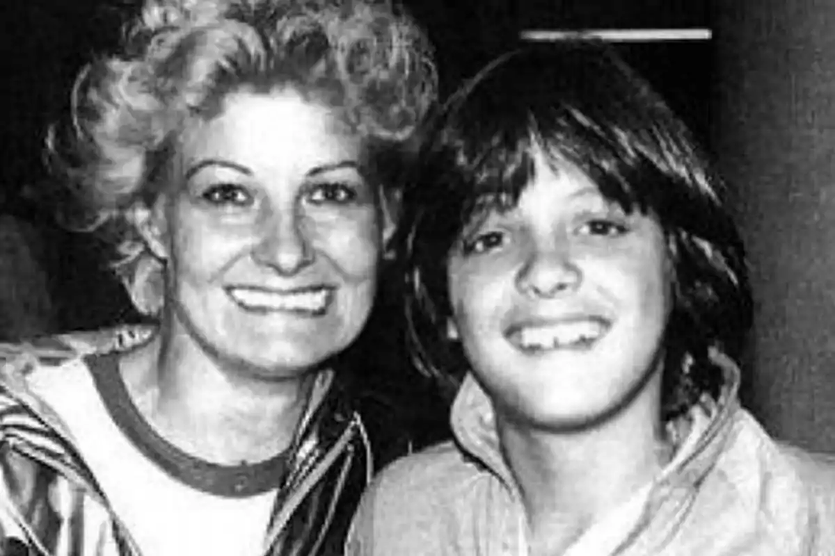 Una mujer y un niño sonríen a la cámara en una fotografía en blanco y negro.