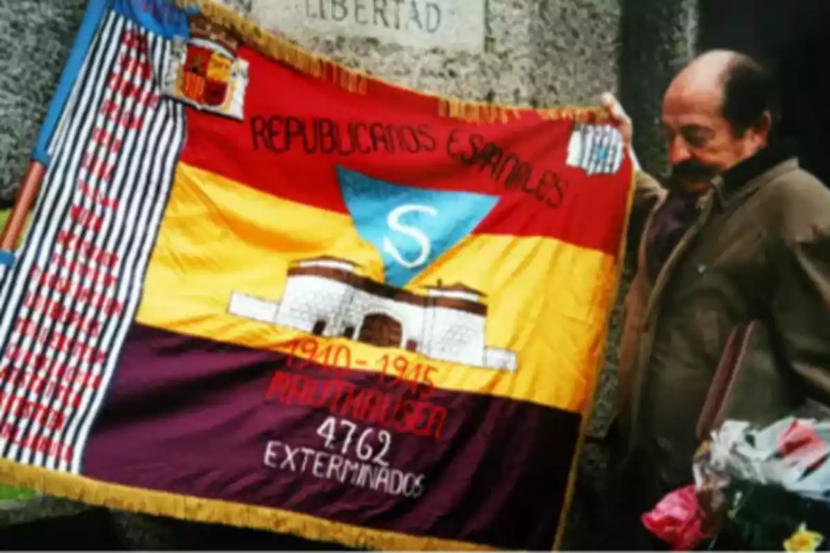 Un hombre sostiene una bandera conmemorativa de los republicanos españoles exterminados en Mauthausen entre 1940 y 1945.